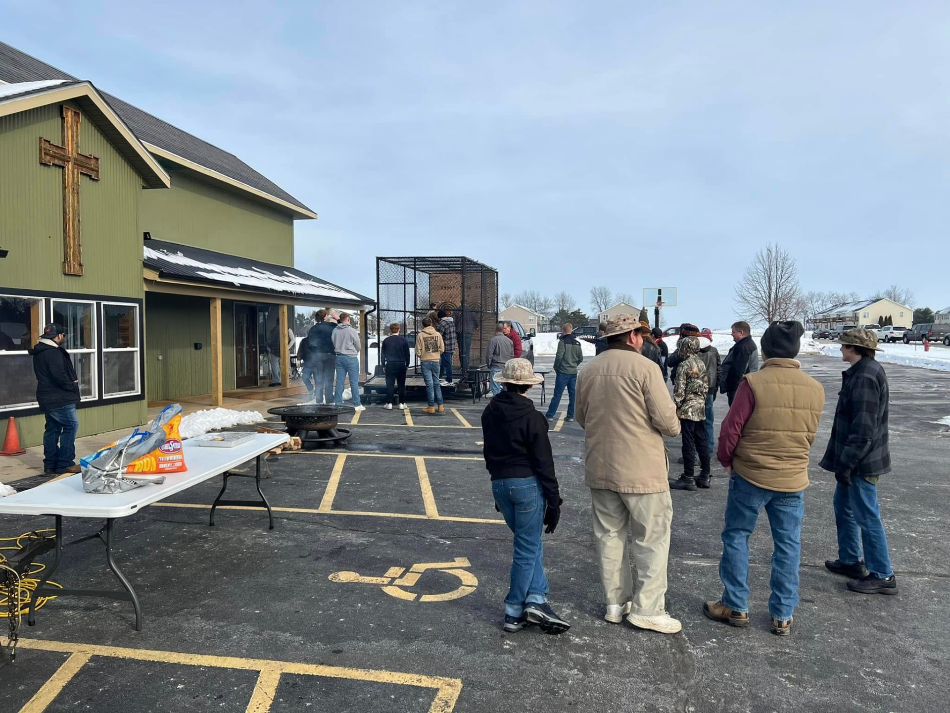 Men gathered outside around a fire pit on a winter morning